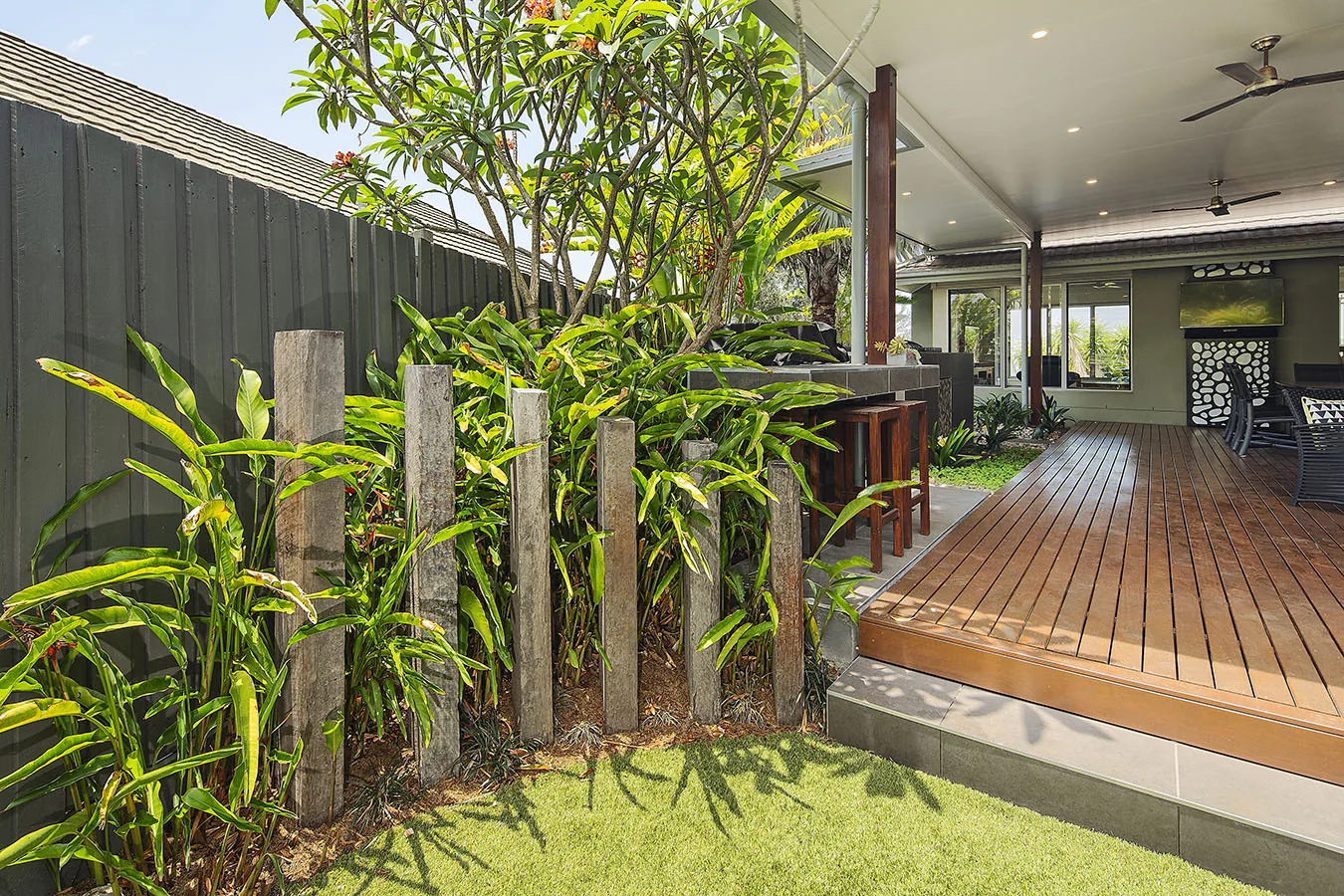 Timber deck walkway framed by layered tropical planting and dappled light